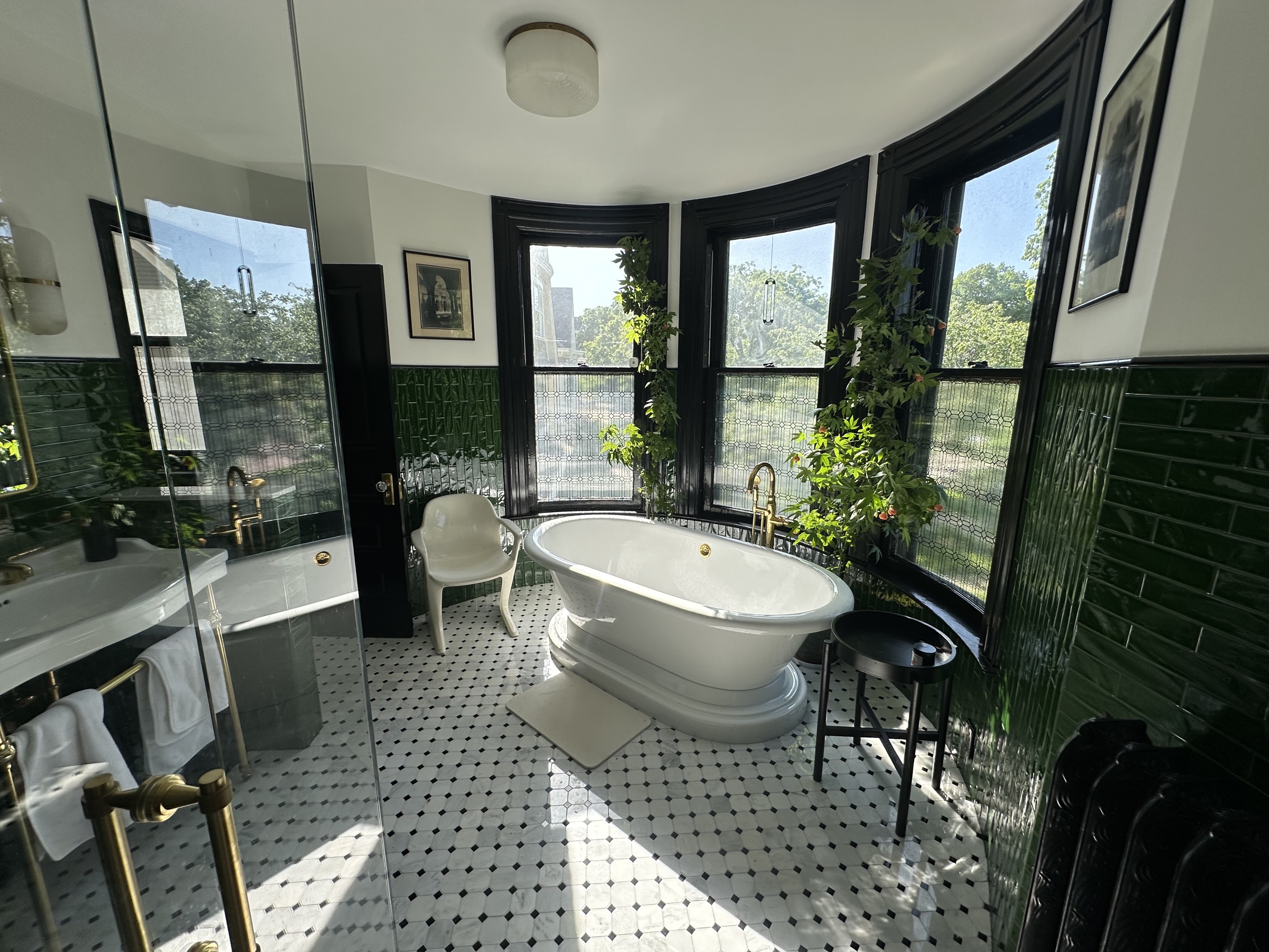Primary bathroom in green subway tile with a deep soaking tub and brass fittings.