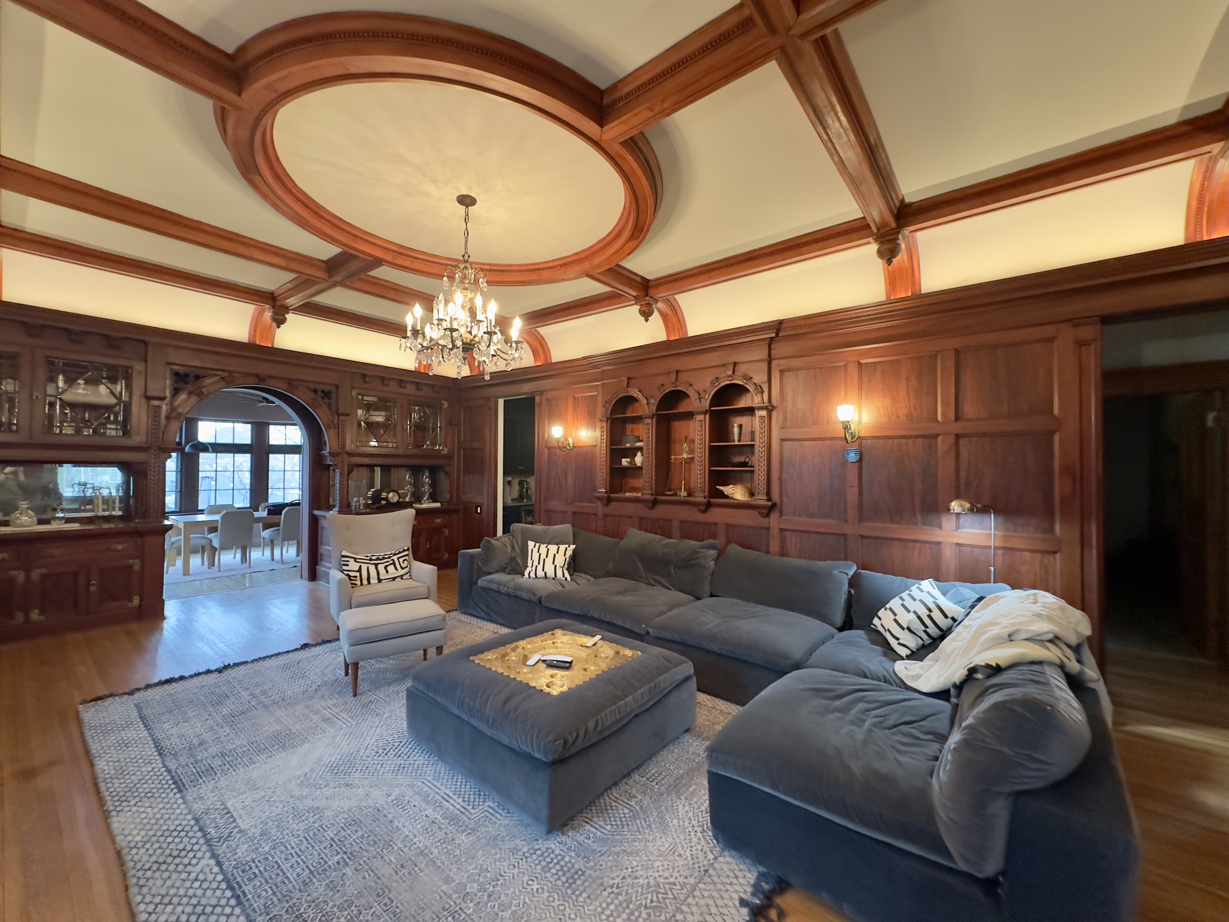The great room at 638 Summit Avenue — coffered ceiling, blue velvet sectional, fireplace ready for cocktail hour.